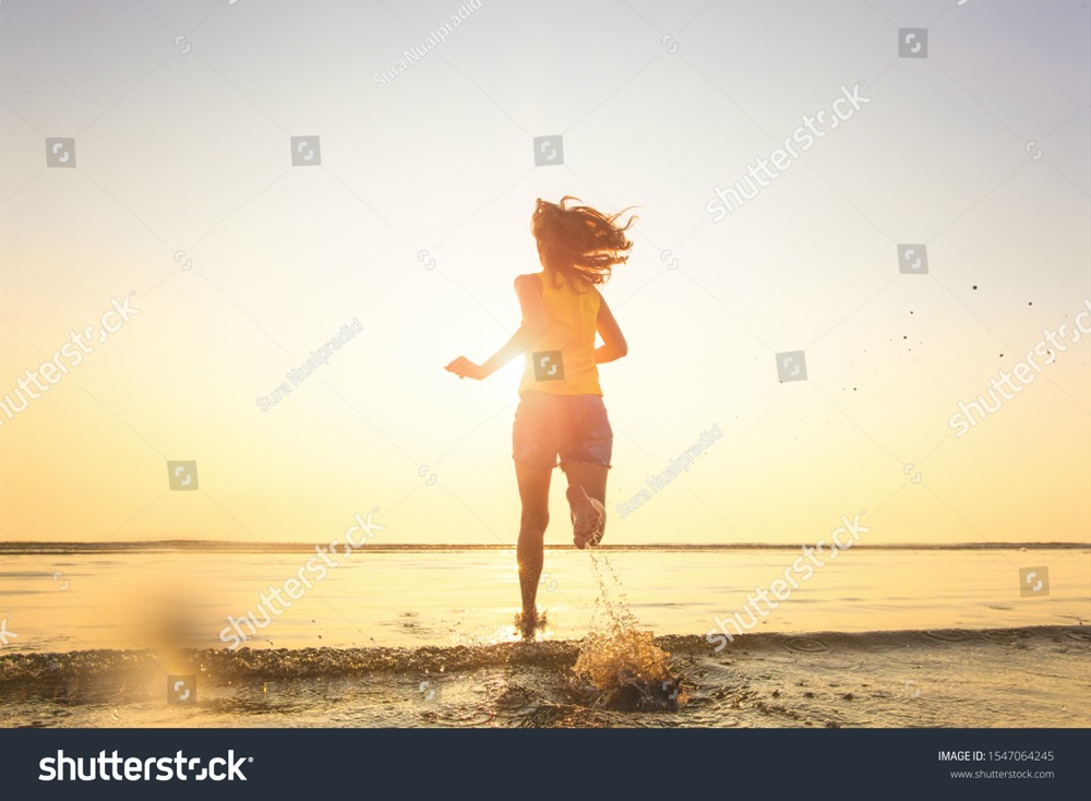 stock photo woman running from beach into seawater with happiness and excited feeling when seeing morning 1547064245