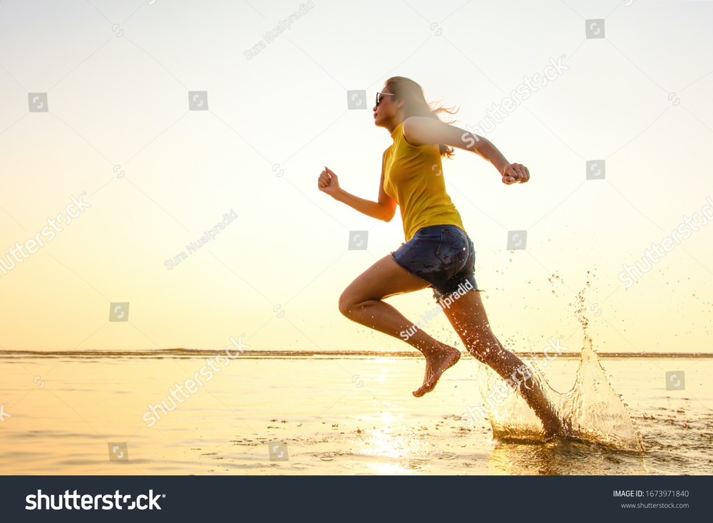 stock photo barefoot woman running jogging in the shallow water on beach in sunlight of morning there are 1673971840