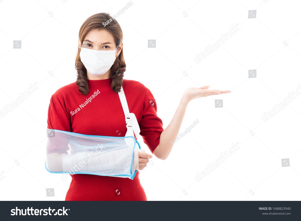 stock photo beautiful asian woman with broken arm and bandage wearing surgical protective hygiene mask standing 1688823940